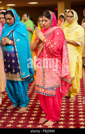 Un groupe de femmes priant et méditant comme invités à une cérémonie de mariage dans le temple à la Sikh Society à Richmond Hill, Queens, New York. Banque D'Images