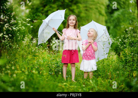 Deux mignonnes petites soeurs des parasols sur une journée en plein air l'été pluvieux Banque D'Images