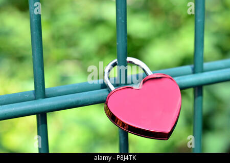 Cadenas en forme de cœur se bloque sur les barres d'une clôture d'exprimer l'amour éternel Banque D'Images