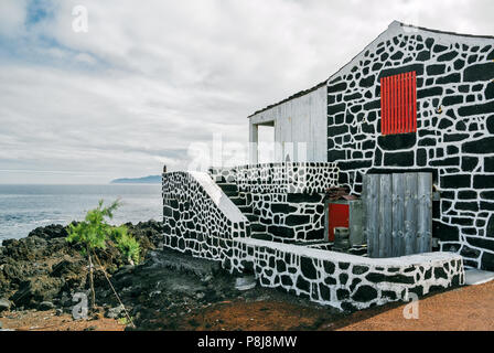 Une maison traditionnelle faite avec des roches volcaniques sombres dans un village sur l'île de Pico, Açores, Portugal. Banque D'Images