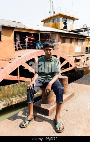 Hularhat, Bangladesh, le 27 février 2017 : un adolescent se trouve en face de la fusée - un ancien bateau à aubes à l'embarcadère d'Hularat Banque D'Images