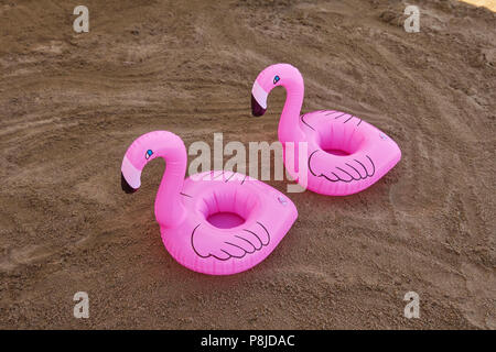 Porte-boisson flamants gonflable sur la plage de sable dans une journée ensoleillée de l'été. Banque D'Images