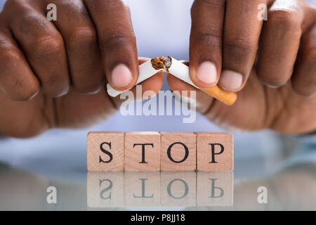 Close-up of a person's Hand Breaking cigarette sur les butoirs Sur le bureau Banque D'Images