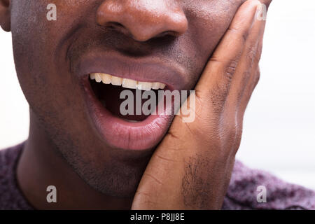 Portrait d'un homme ayant mal aux dents contre fond blanc Banque D'Images