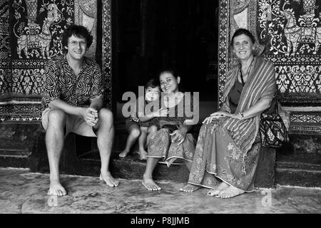 Famille dans l'embrasure de Wat Xieng Thong (Temple de la ville d'Or) , construit en 1560 - LUANG PRABANG, LAOS M. Banque D'Images