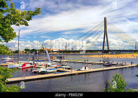 Yachts blancs avec de grands mâts contre le panorama de la ville de Riga avec spiers de cathédrales et d'un pont à haubans sur la Daugava sur Banque D'Images