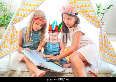 Trois jolie fille jouer et lire ensemble à l'intérieur Banque D'Images