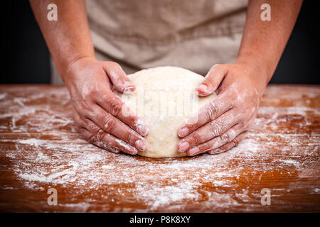 Baker mains faire du pain au levain sur une table en bois Banque D'Images