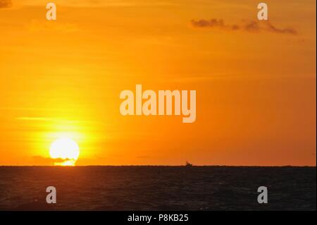 Colorés, partiellement nuageux coucher du soleil orange avec silhouette de bateaux bateau de pêche en excès de distance sur l'Océan Atlantique comme vu à partir de la Floride, aux États-Unis. Banque D'Images