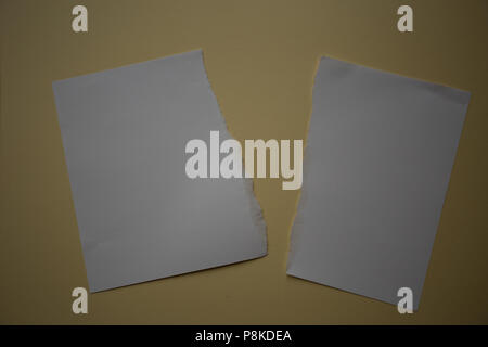 Un morceau de papier blanc déchiré dans la moitié sur fond jaune Banque D'Images