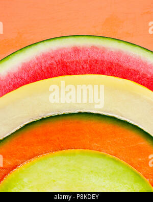 Résumé de quatre différents types de melon très coloful dans un arc-en-ciel vetical format idéal pour les en-têtes, fond orange , prix pour le texte et l'espace de copie Banque D'Images