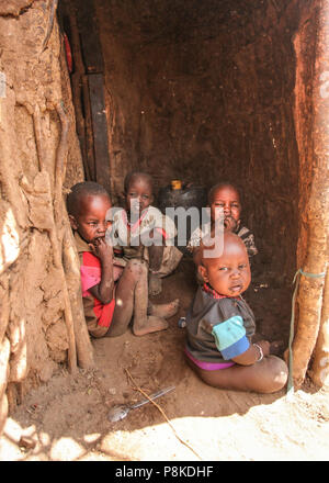 Inconnu Masai village près de parc Amboselli, Kenya - 02 avril, 2015 : Groupe de pauvres enfants sale avec des visages et la bouche couverte de mouches assis à ent Banque D'Images