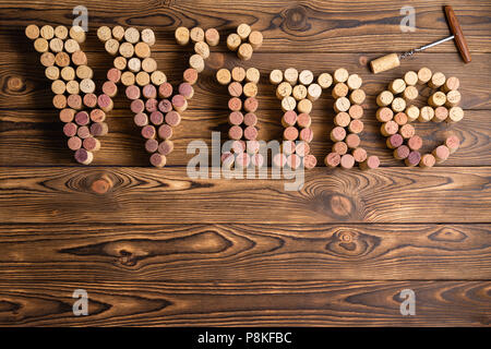 Vin mot formé de vin rouge et blanc bouchons en couleurs sur un fond en bois rustique avec un ouvreur ou tire-bouchon et copy space Banque D'Images