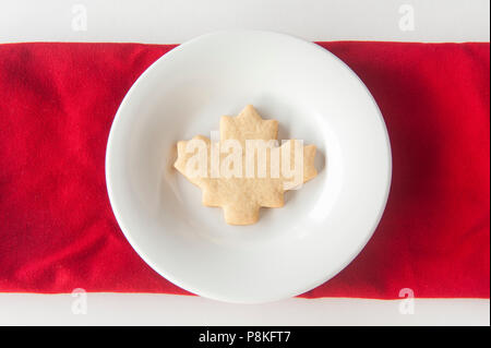 Un biscuit en forme de la feuille d'érable sur une plaque blanche ronde Banque D'Images