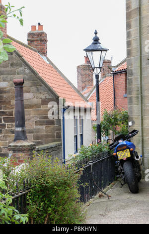 Stationné dans la cour de l'église de moto à Robin Hood's Bay,Yorkshire,Angleterre,Heritage Coast UK après longue pression à travers les rues étroites Banque D'Images