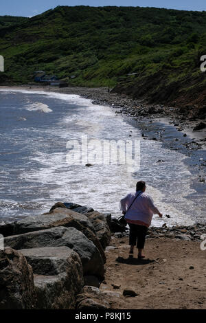 Les vacanciers et les personnes à pied les rochers sur la plage avec un chien par la mer à Runswick Bay, North Yorkshire Heritage Coast. Banque D'Images