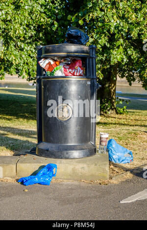 Corbeille pleine débordant de détritus sur le dessus et autour d'elle sur le terrain, Lancashire, England, UK Banque D'Images