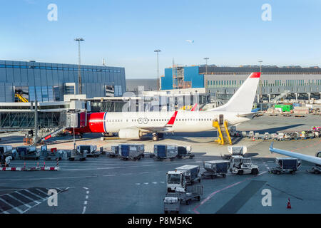 Avion chargement parqué par bâtiment de l'aéroport de Copenhague, les escaliers et les porte-bagages à proximité Banque D'Images