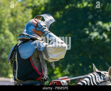 Joutage médiéval, palais de Linlithgow, Écosse, Royaume-Uni. HES été divertissement par l'équipe de cascades les amis d'Onno équine comme un chevalier met sur un casque médiéval Banque D'Images