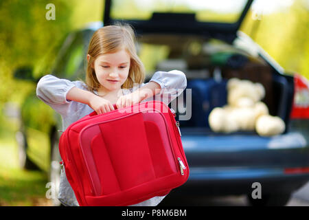 Adorable petite fille avec une valise de partir pour une location de vacances avec ses parents Banque D'Images