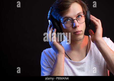 Portrait de jeune homme à l'écoute de chanson préférée avec attention fond noir isolé Banque D'Images