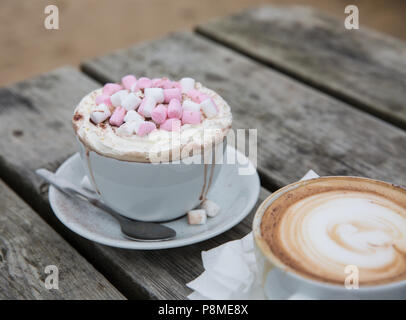 Un luxe de boire un chocolat chaud dans une tasse et soucoupe chic avec de la crème fouettée et les guimauves et de fusion en bas de la tasse de dribbles Banque D'Images