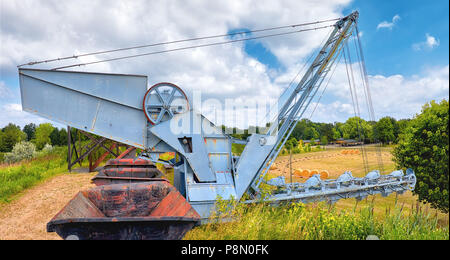 Chaîne vieux seau pelle et d'une rangée de vagons de charbon sur une colline d'herbe à l'extérieur. Image panoramique prises dans le Brandebourg, Allemagne. Banque D'Images