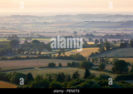 Vue sur les terres agricoles de la lumière du soleil du matin brumeux dans Warwickshire pris de la valeur au-dessus du village d'Ilmington, les Cotswolds, Warwickshire, Angleterre Banque D'Images