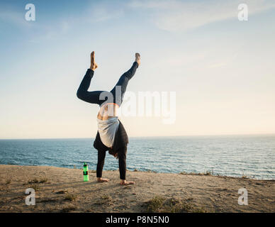 Man doing handstand on beach Banque D'Images