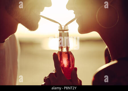 Close up of romantic couple boivent des boissons avec des pailles d'une bouteille. Couple aimant le partage d'une boisson. Banque D'Images