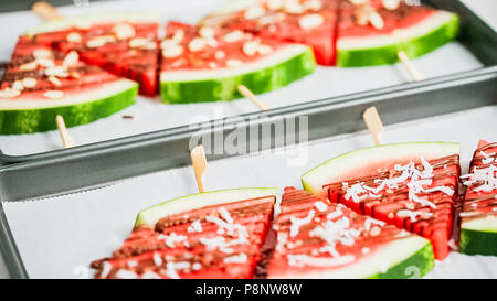 Étape par étape. Quartiers de pastèque garnie avec du chocolat et du sel de mer sur le stick sur une tôle à biscuits. Banque D'Images