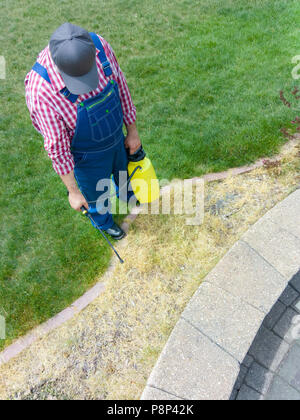 Man spraying weed killer sur spring grass dans un parterre nouvellement délimitées comme il se prépare pour le paillage et plantation Banque D'Images