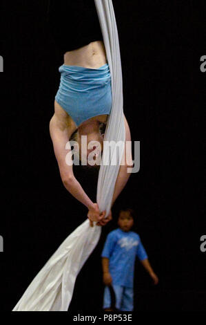 Un jeune garçon regarde une femme acrobat suspend l'envers elle-même avec l'utilisation de soies aériennes. Banque D'Images