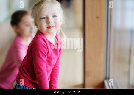 Deux adorables petites soeurs assis près de la fenêtre à la maison Banque D'Images