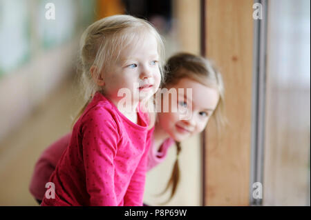 Deux adorables petites soeurs assis près de la fenêtre à la maison Banque D'Images