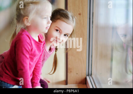 Deux adorables petites soeurs assis près de la fenêtre à la maison Banque D'Images