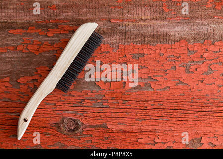 Brosse de nettoyage en bois contre l'arrière-plan avec la peinture rouge sortant Banque D'Images