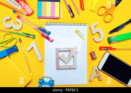 Les élections scolaires concept. Case d'élection et les accessoires sur un 24 sur un fond jaune. l'éducation. papeterie, des montres, des stylos de couleur, ph Banque D'Images