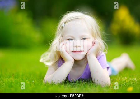 Cute little girl pose dans l'herbe sur un jour d'été ensoleillé Banque D'Images