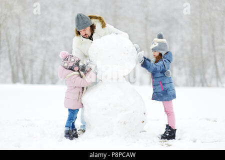 Jeune père de famille et ses deux filles un bonhomme sur journée d'hiver Banque D'Images