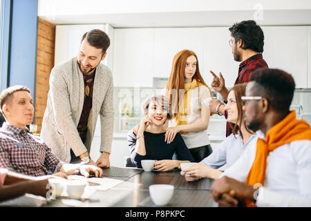 La photo en gros de jeunes employés diversifiés bénéficiant pendant les pauses café Banque D'Images