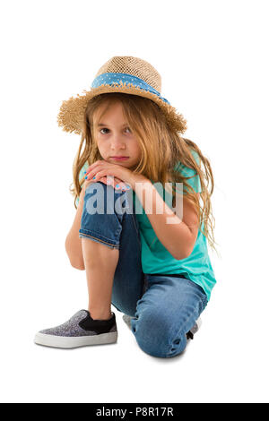 Petite fille solennelle déprimé à regarder la caméra comme elle s'agenouille posant son menton sur son genou isolated on white Banque D'Images