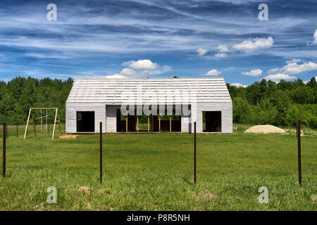 Le cadre d'une nouvelle maison de campagne avec une rotation de l'enfant dans le contexte de la forêt et le ciel bleu sur une journée ensoleillée d'été. Banque D'Images