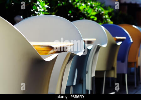 Multi-couleur en plastique chaises et tables en bois dans un café d'été Banque D'Images