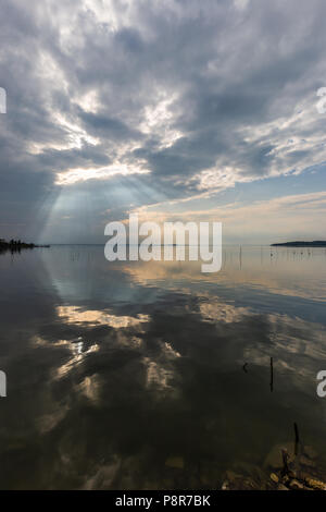 Parfaitement symétrique et vue spectaculaire d'un lac, avec des nuages, le ciel et les rayons du soleil reflétant sur l'eau Banque D'Images