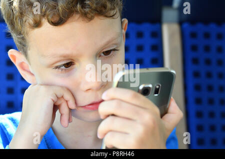 Visage d'un garçon jouant avec un smartphone en mode portrait size Banque D'Images