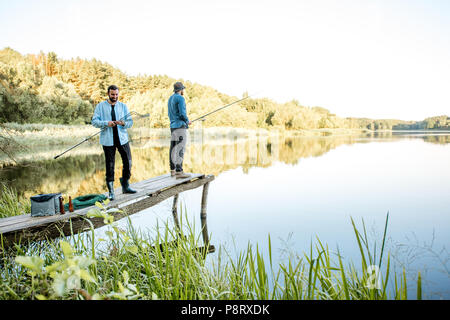 Deux amis pour la préparation de commandes de pêche avec filet de pêche et d'accouplement sur la jetée en bois au cours de la lumière du matin sur le lac Banque D'Images