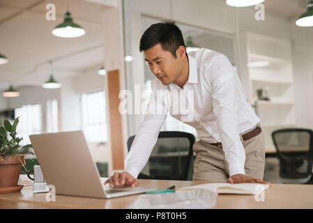L'accent Young Asian Woman en ligne à son bureau 24 Banque D'Images