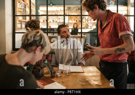 Amis assis dans un restaurant de l'alimentation commande de serveur Banque D'Images