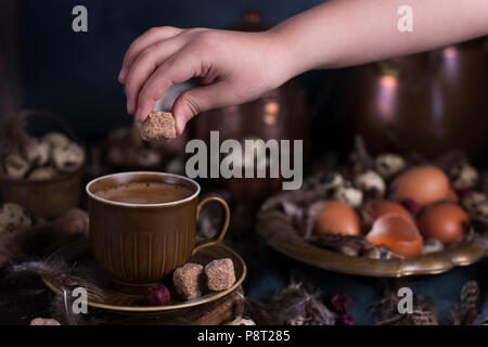 Les mains des enfants dans le cadre d'oeufs de Pâques, grandes et petites, des plumes. Photo dans le style vintage. Accessoires rural. Copy space Banque D'Images